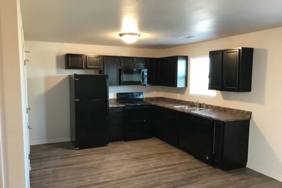 A Parkside Manor kitchen with dark cabinets, a refrigerator, a range with a microwave above it, a dishwasher beside the sink and a laminate counter.