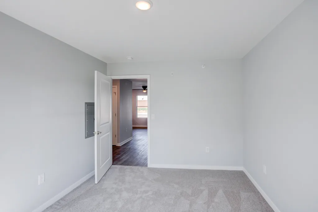 An unfurnished Cypress Point bedroom with a window, carpet, ceiling fan and closet doors.