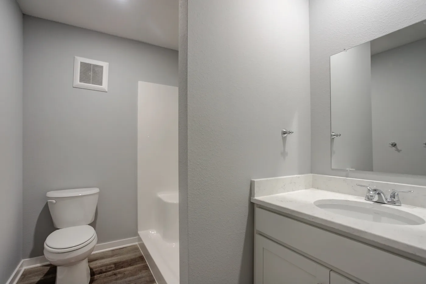 An Orchard Estates bathroom with a white vanity, toilet and bathtub with shower surround.