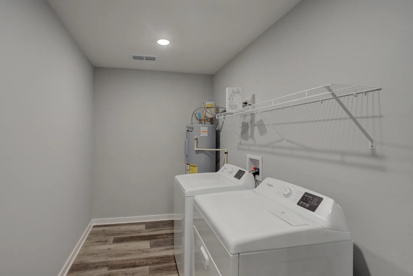 The Orchard Estates laundry room with a washer, dryer, utility shelf and water heater.