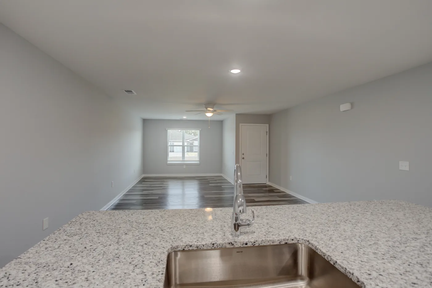 The open living area in an Orchard Estates duplex, viewed from the kitchen across the island and wood-look floor.